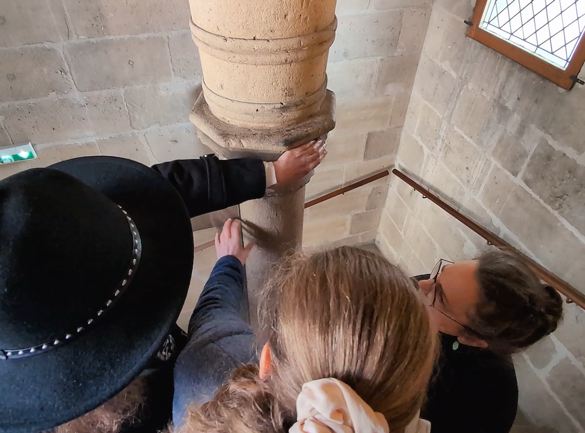 3 personnes explorent le pilier central de l'escalier à vis de la tour Jean Sans Peur