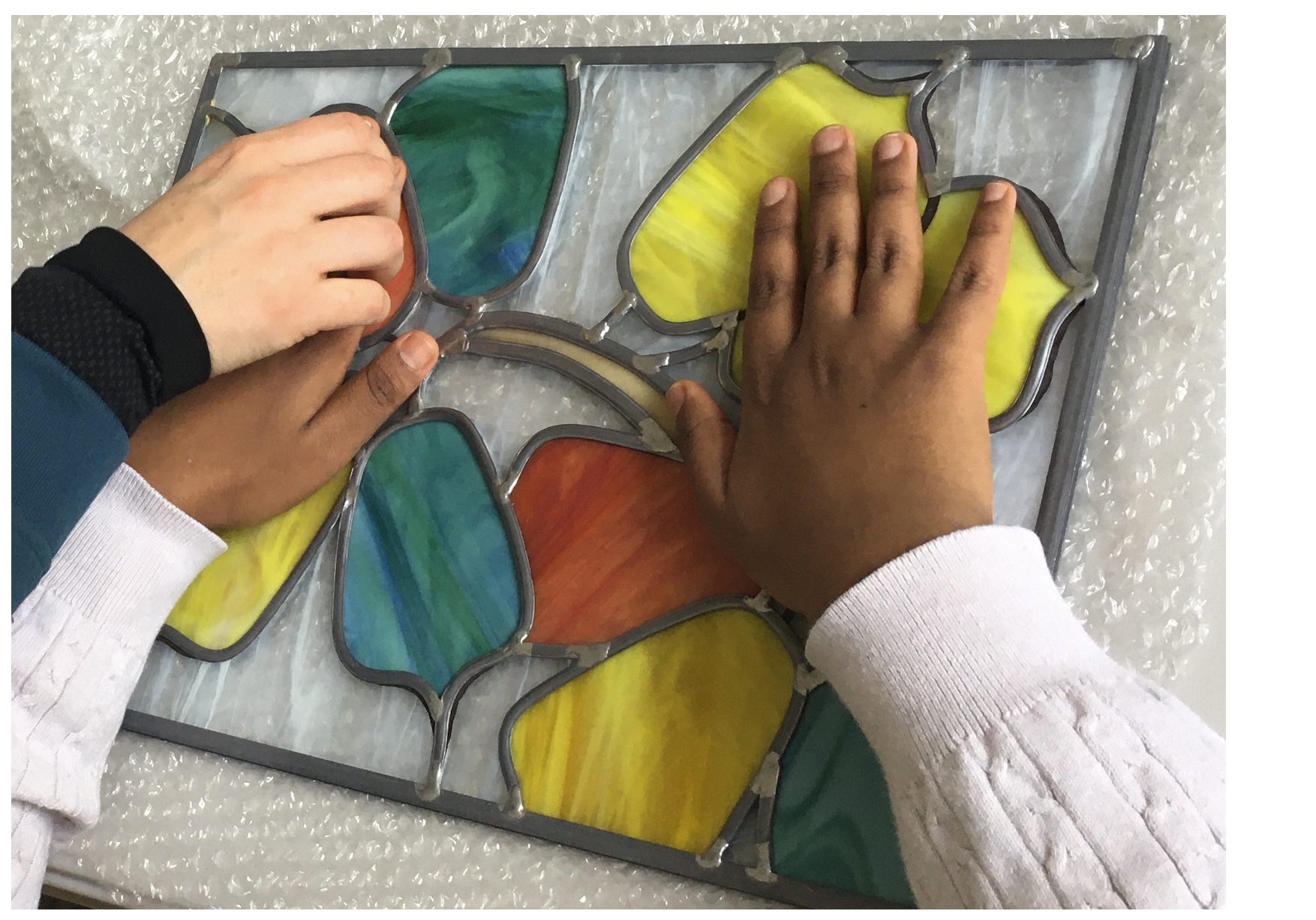 Mains touchant un vitrail.