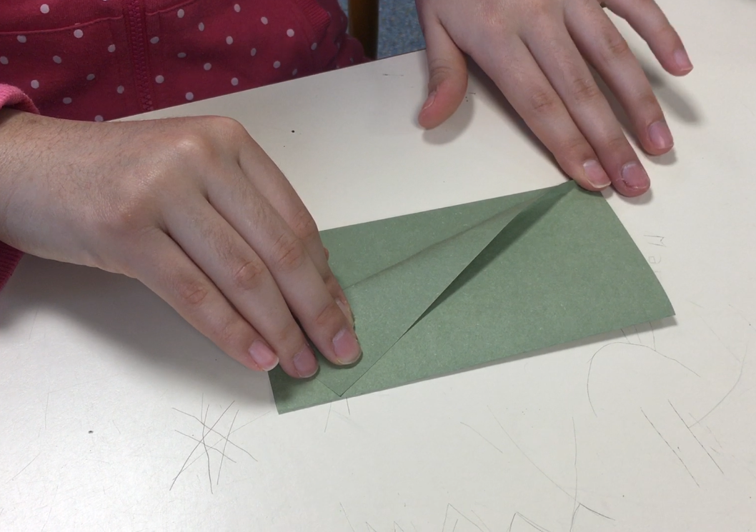 Une élève plie un carré de papier